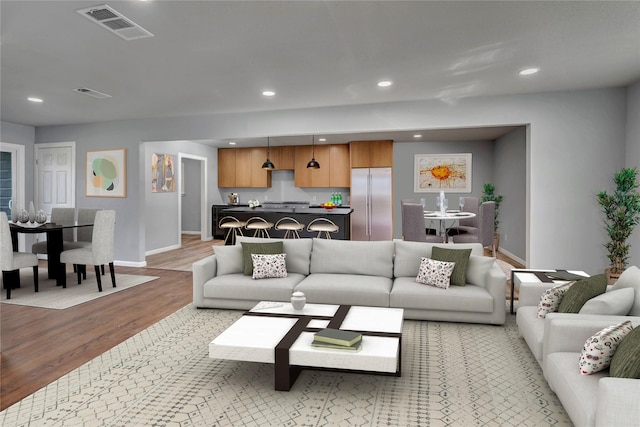 living room featuring light wood-type flooring, visible vents, and recessed lighting