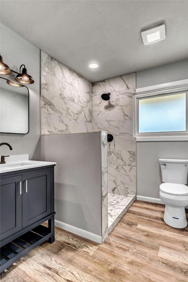 full bathroom featuring a walk in shower, toilet, wood finished floors, and vanity