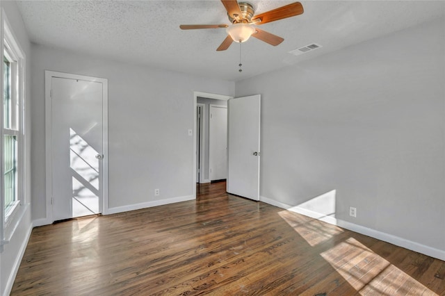 unfurnished bedroom with multiple windows, visible vents, and wood finished floors