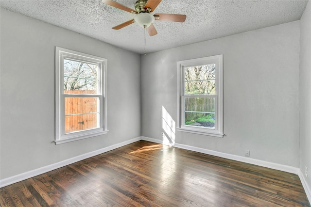 empty room featuring a textured ceiling, ceiling fan, wood finished floors, and baseboards