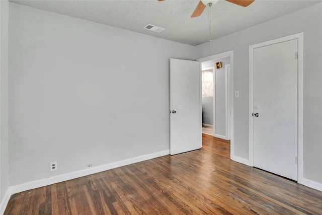 unfurnished bedroom with visible vents, a textured ceiling, baseboards, and wood finished floors