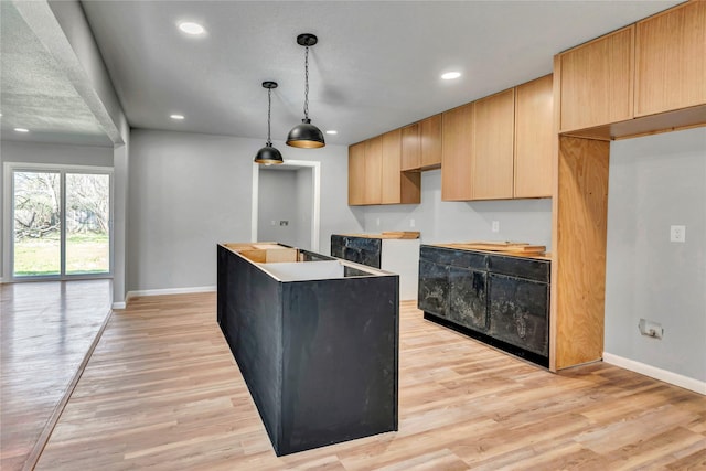 kitchen with a center island, baseboards, light wood finished floors, and recessed lighting