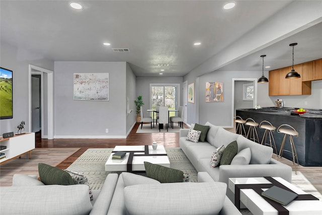 living area with recessed lighting, visible vents, and wood finished floors