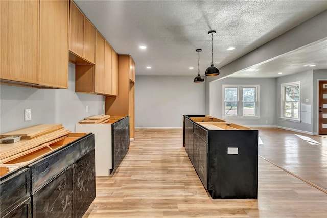 kitchen with a textured ceiling, recessed lighting, baseboards, a center island, and light wood finished floors