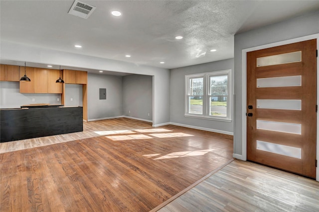 interior space featuring light wood finished floors, electric panel, baseboards, visible vents, and recessed lighting