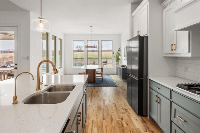 kitchen with custom range hood, backsplash, appliances with stainless steel finishes, a sink, and light wood-type flooring