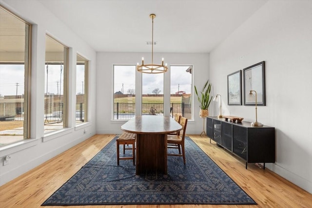 dining space featuring light wood-style floors, baseboards, visible vents, and a chandelier