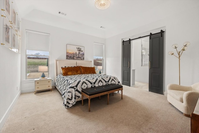 bedroom with light carpet, a barn door, visible vents, and baseboards