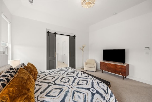 bedroom with carpet flooring, visible vents, baseboards, and a barn door