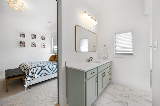 bathroom featuring marble finish floor, baseboards, vanity, and ensuite bath