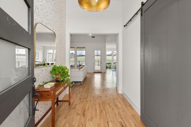 hall featuring light wood-style floors, a barn door, and arched walkways