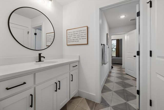 ensuite bathroom featuring connected bathroom, vanity, baseboards, visible vents, and tile patterned floors