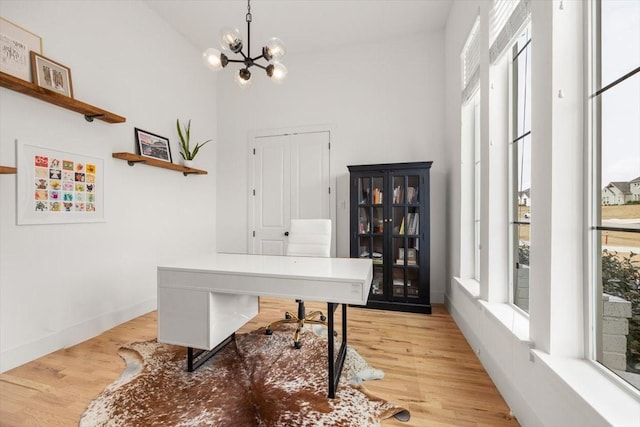 office area with baseboards, a chandelier, and wood finished floors