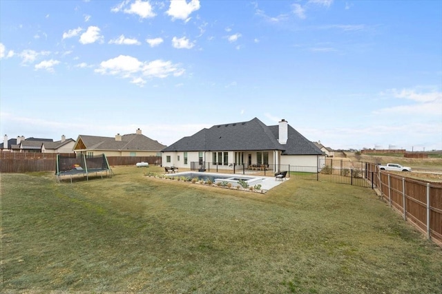 back of property with a trampoline, a fenced in pool, a patio, a lawn, and a fenced backyard