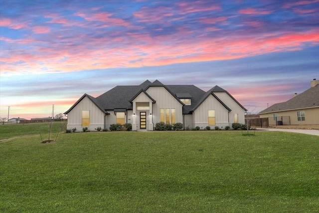 modern inspired farmhouse with board and batten siding, a lawn, and a shingled roof