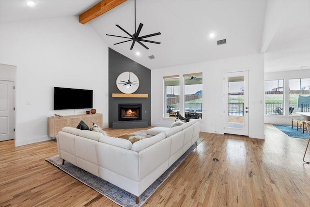 living room featuring light wood-type flooring, a wealth of natural light, a fireplace, and visible vents