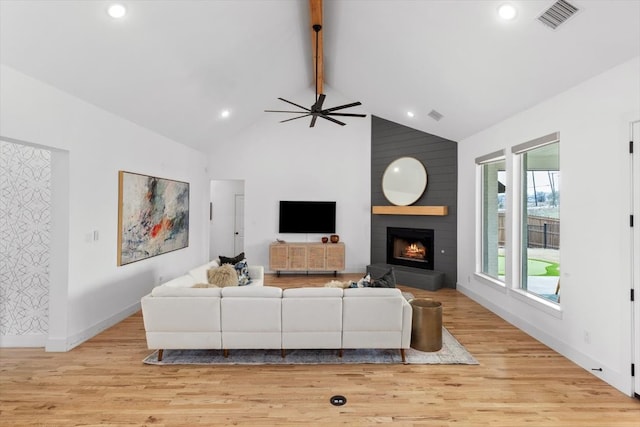 living room with beam ceiling, visible vents, a large fireplace, light wood-type flooring, and baseboards