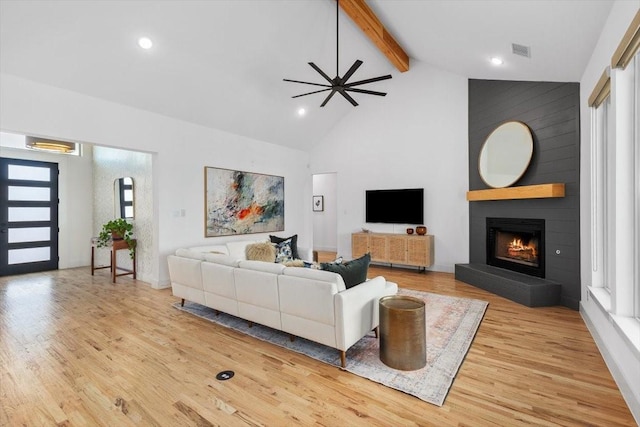 living room with high vaulted ceiling, a large fireplace, beamed ceiling, and wood finished floors