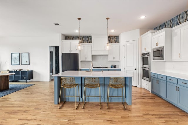 kitchen featuring stainless steel appliances, light countertops, visible vents, and light wood-style flooring