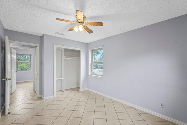 unfurnished bedroom featuring light tile patterned floors, visible vents, multiple windows, and a closet