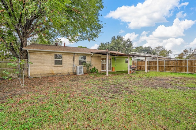 back of property featuring brick siding, central air condition unit, a lawn, and a fenced backyard