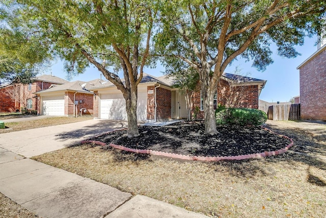 ranch-style home featuring a garage, concrete driveway, brick siding, and fence