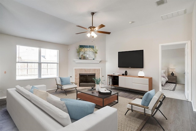 living area featuring lofted ceiling, a fireplace, wood finished floors, and visible vents