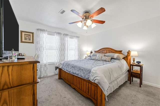 bedroom with light carpet, a ceiling fan, visible vents, and baseboards