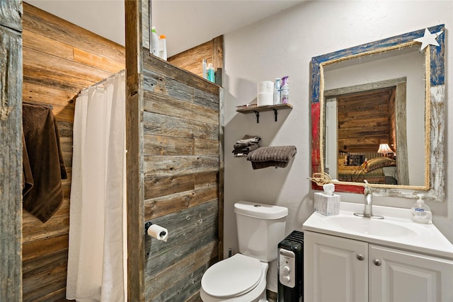 full bathroom with vanity, toilet, and wooden walls