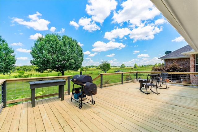 deck with a rural view, a lawn, and area for grilling