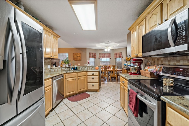 kitchen featuring light brown cabinetry, appliances with stainless steel finishes, light tile patterned flooring, and a peninsula