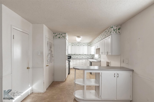 kitchen with black microwave, light countertops, a textured ceiling, white cabinetry, and open shelves