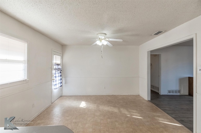 spare room with a ceiling fan, visible vents, a textured ceiling, and tile patterned floors