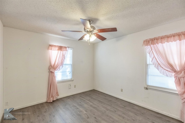 spare room with a textured ceiling, wood finished floors, a ceiling fan, and baseboards