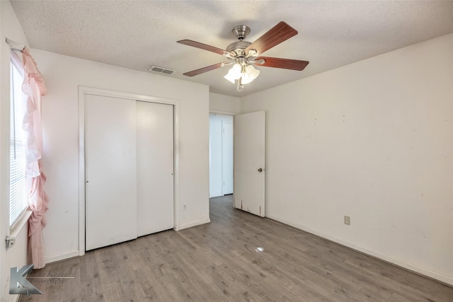 unfurnished bedroom with visible vents, ceiling fan, wood finished floors, a textured ceiling, and a closet