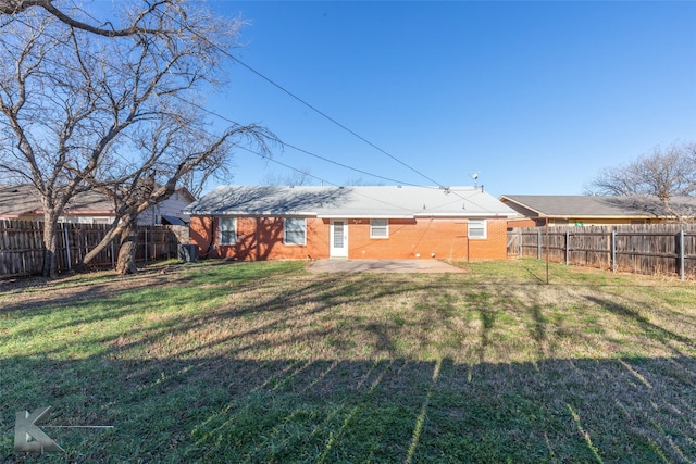 rear view of property with a yard, brick siding, a patio, and a fenced backyard