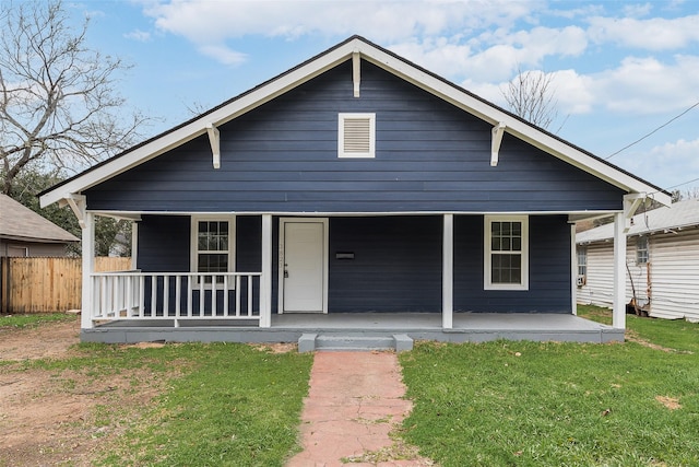 bungalow-style house with covered porch, fence, and a front lawn