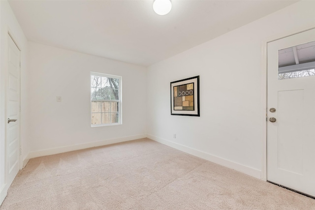 spare room with baseboards and light colored carpet