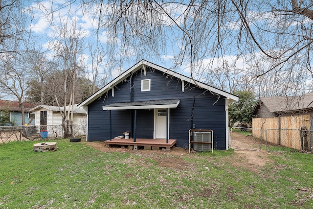 back of property with a yard, fence, and a fire pit