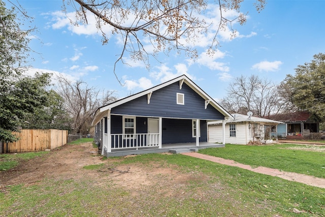 bungalow with covered porch, fence, and a front lawn