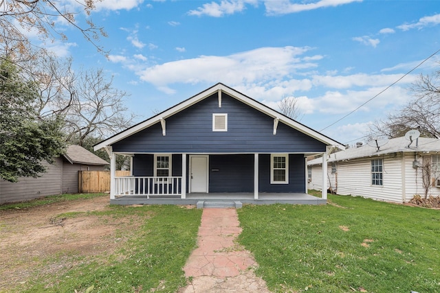 bungalow-style house with covered porch, fence, and a front lawn