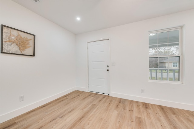 spare room with baseboards and light wood-style floors