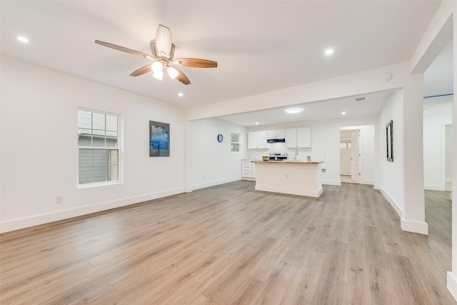 unfurnished living room with baseboards, ceiling fan, and light wood-style floors