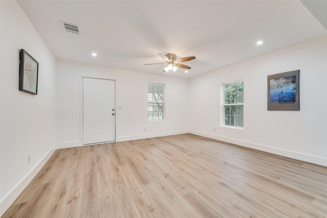 empty room featuring light wood finished floors, baseboards, visible vents, and ceiling fan