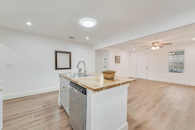 kitchen featuring butcher block counters, a kitchen island with sink, a sink, light wood-type flooring, and dishwasher