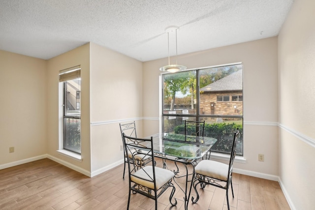 dining space with a textured ceiling, wood finished floors, and baseboards