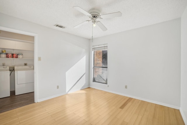 spare room with a textured ceiling, light wood-style floors, a ceiling fan, and washer and dryer