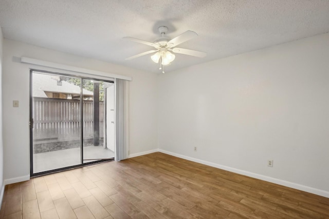 empty room with ceiling fan, a textured ceiling, baseboards, and wood finished floors