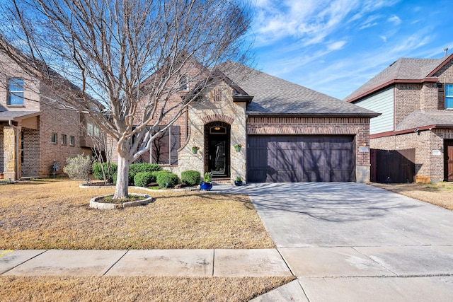 french country home with a garage, driveway, stone siding, roof with shingles, and brick siding