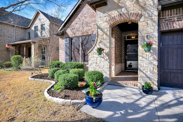 doorway to property featuring stone siding and brick siding